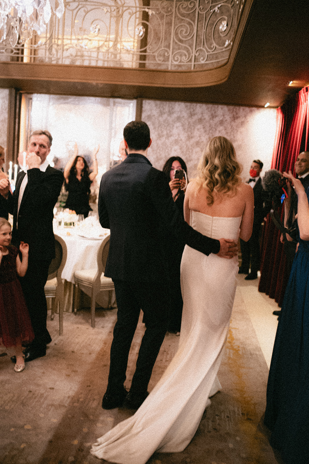 Bride and groom entering dinner at Hôtel Plaza Athénée surrounded by guests